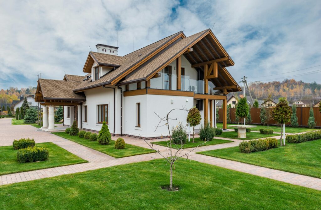 pexels-photo-5997994-5997994 Exterior of modern cottage house with columns and balcony surrounded by green grass and trees